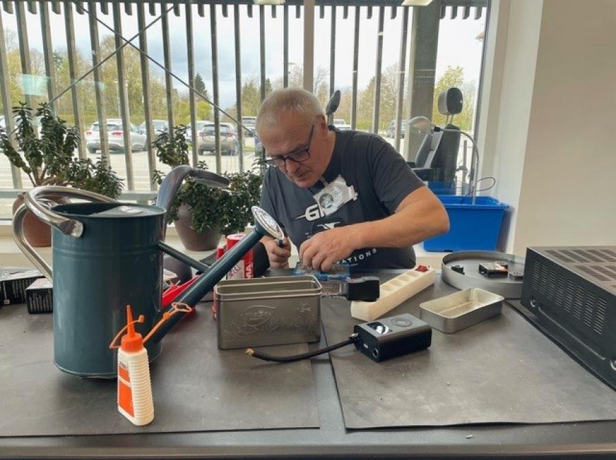 En mand sidder og fikser ting i Repair Caféen